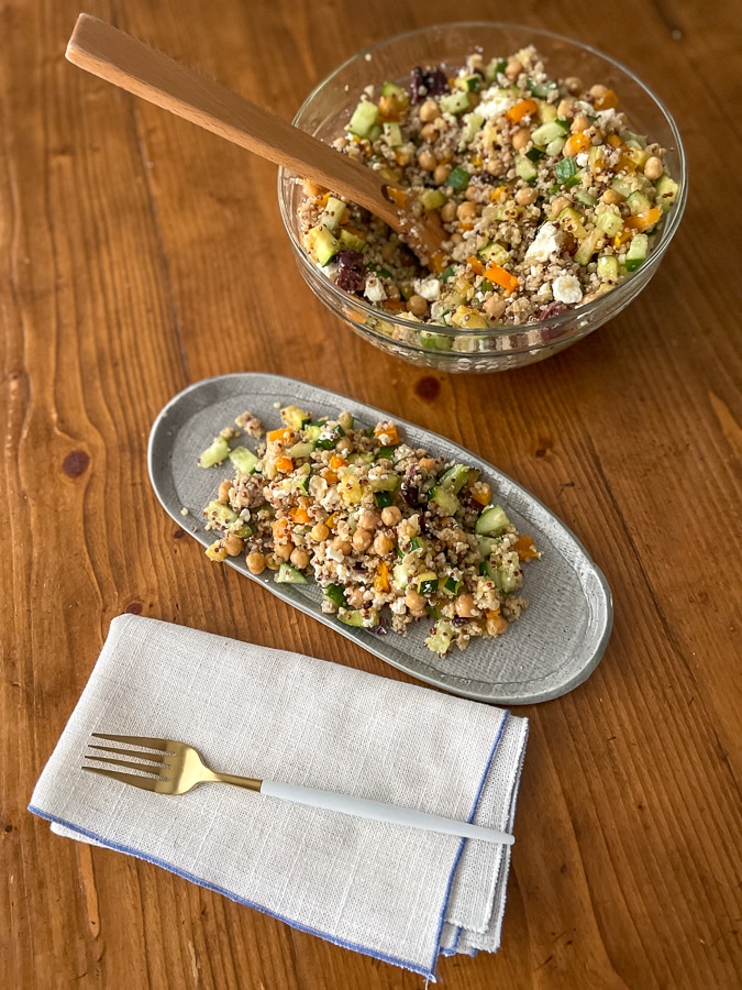 greek salad with quinoa on a gray plate with a napkin and fork