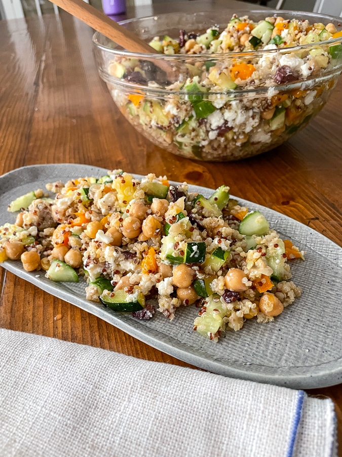 greek salad with quinoa on a gray plate with serving bowl