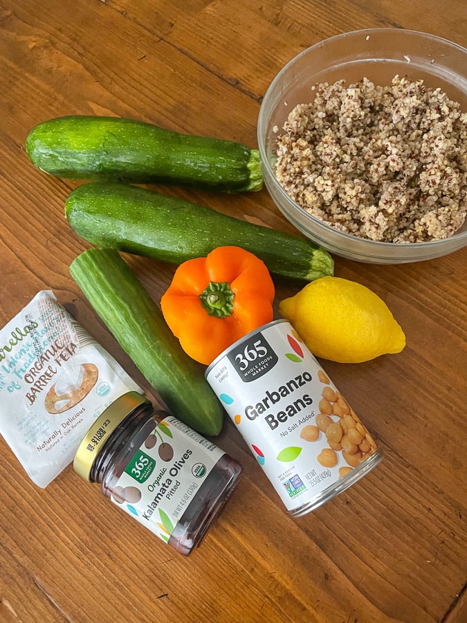 greek salad ingredients with quinoa and millet, zucchini, pepper, lemon, chickpeas, olives and feta