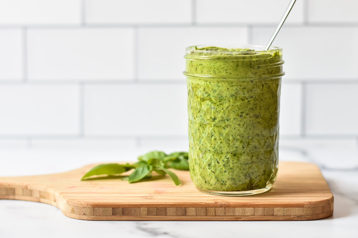 jar of pesto on a cutting board