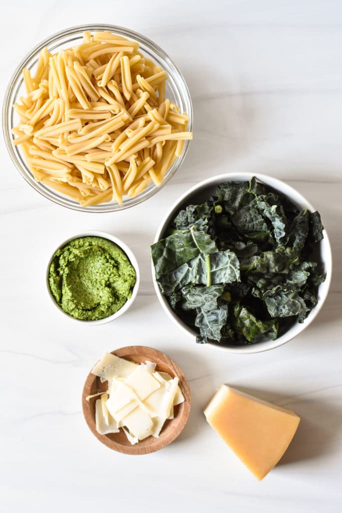 pasta kale pesto and parmesan cheese in separate bowls
