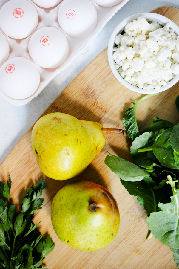 eggs, pear, greens, and cheese on a cutting board