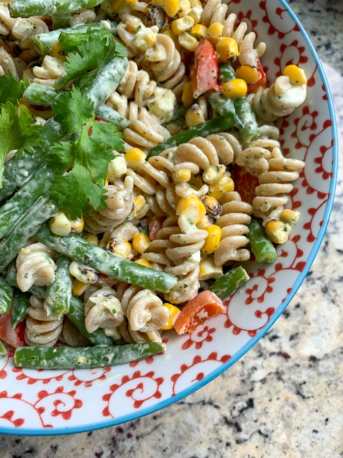 close up of rotini pasta salad with corn, peppers, herbs, and green beans