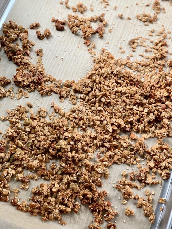 Crunchy Tahini Granola on silver sheet pan with brown parchment paper. 