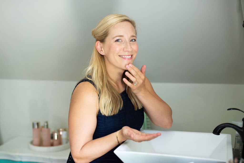 Kath at bathroom sink applying facial cleanser. 