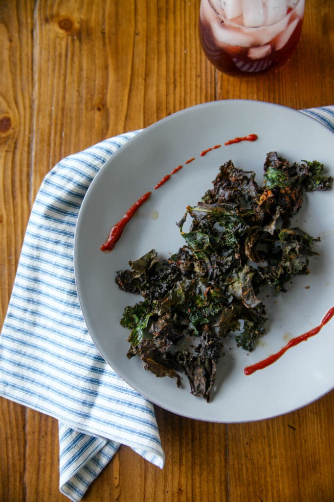 kale chips on a plate with sriracha