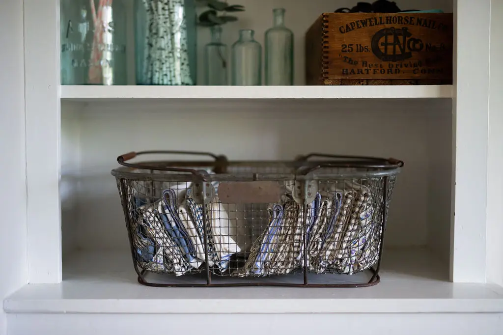Organized shelf with decor and wire basket with linens. 