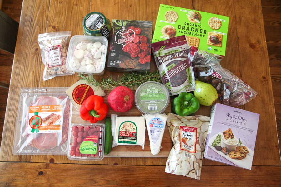 Ingredients for holiday charcuterie board: cheeses, cured meats, crackers, fruits, nuts, herbs and dips