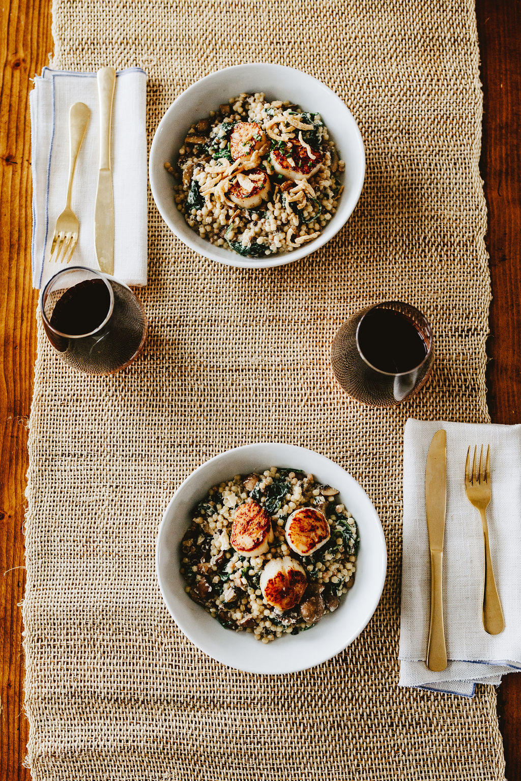 a blue apron premium meal of scallops and pasta with wine and gold silverware