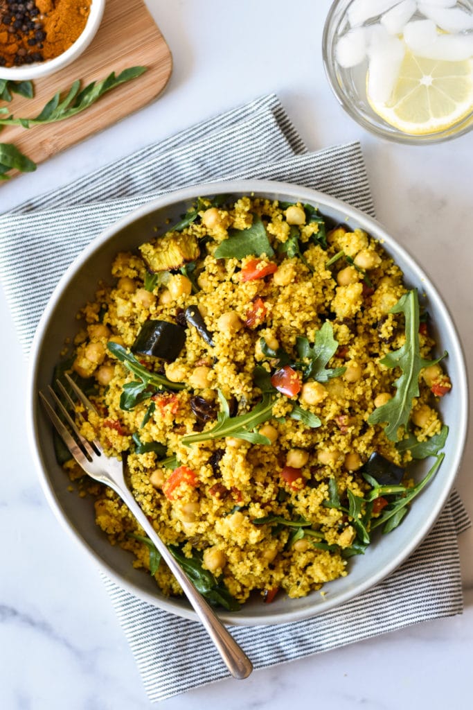 spiced millet salad in a bowl with glass of water
