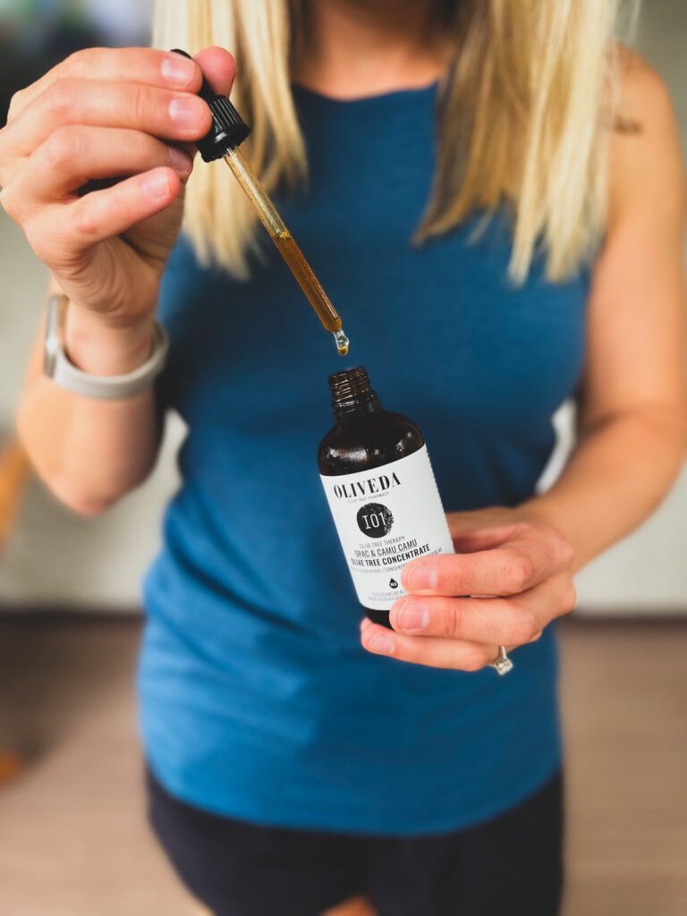 Kath Eats Blogger Kath Younger shares new finds for fall: in photo: Kath showing a bottle and a dropper of I01 HYDROXYTYROSOL + CAMU CAMU OLIVE LEAF CONCENTRATE?